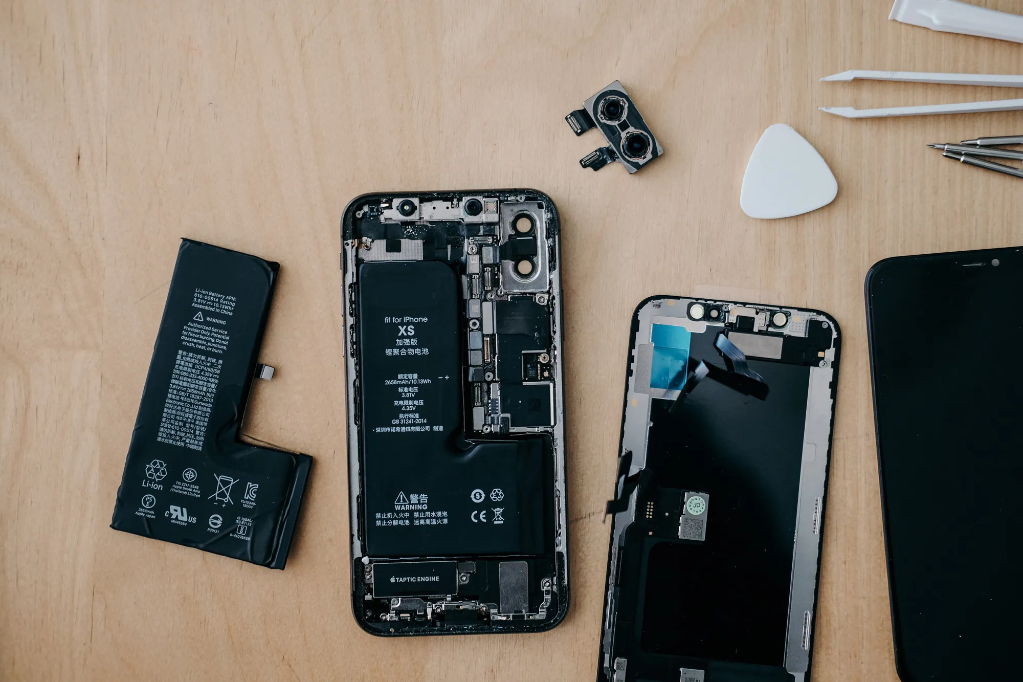 Disassembled smartphone with internal components laid out on a workbench