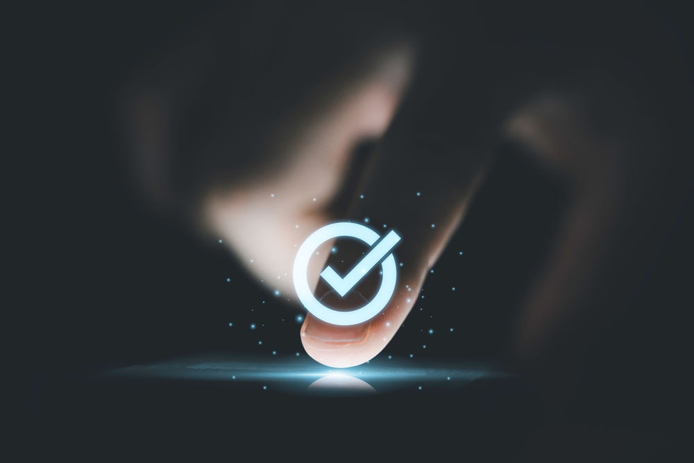 finger pushing button on cell phone with check mark on top