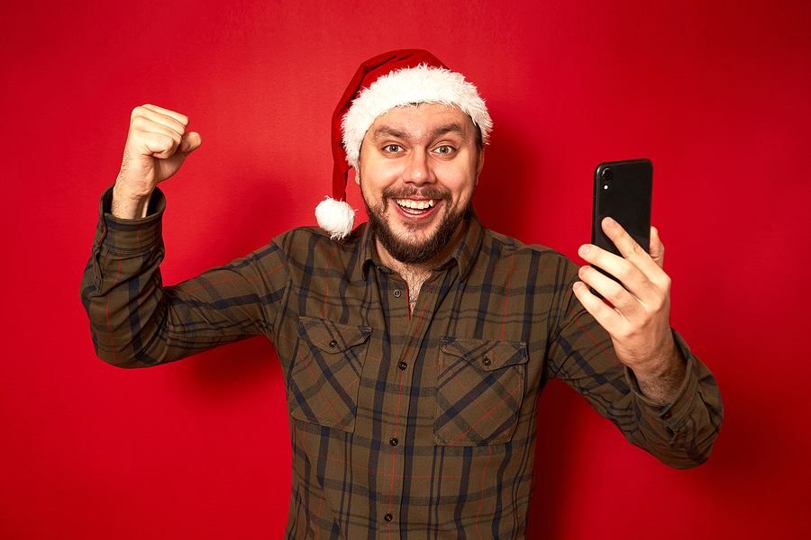 Adult man with a santa hat on excited holding a mobile phone