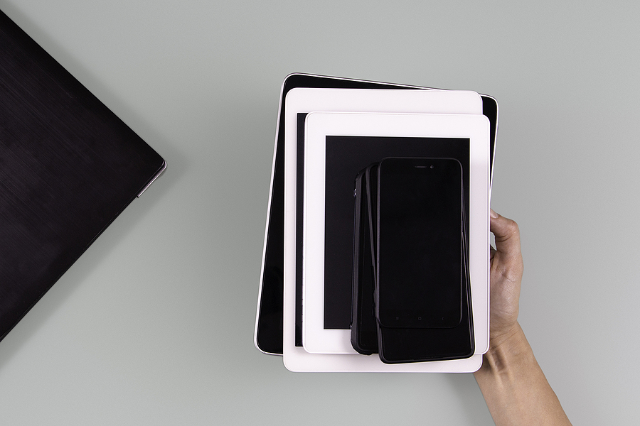 Hand holding stacked mobile devices including smartphones and tablets, symbolizing the growing market and future trends of refurbished phones